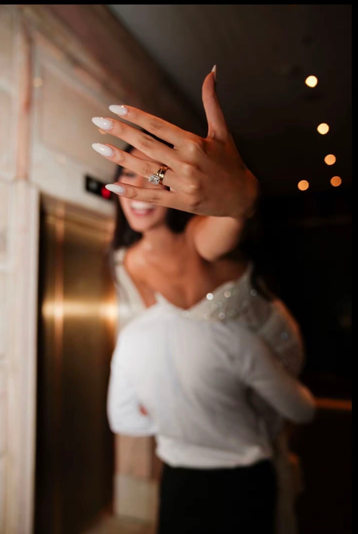 An oval solitaire ring standing on travertine in soft window light