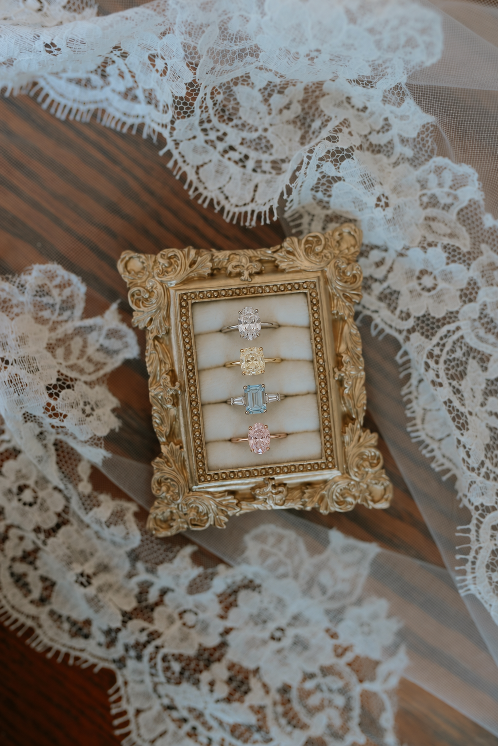 Fine jewelry rings displayed in an ornate gold frame on lace